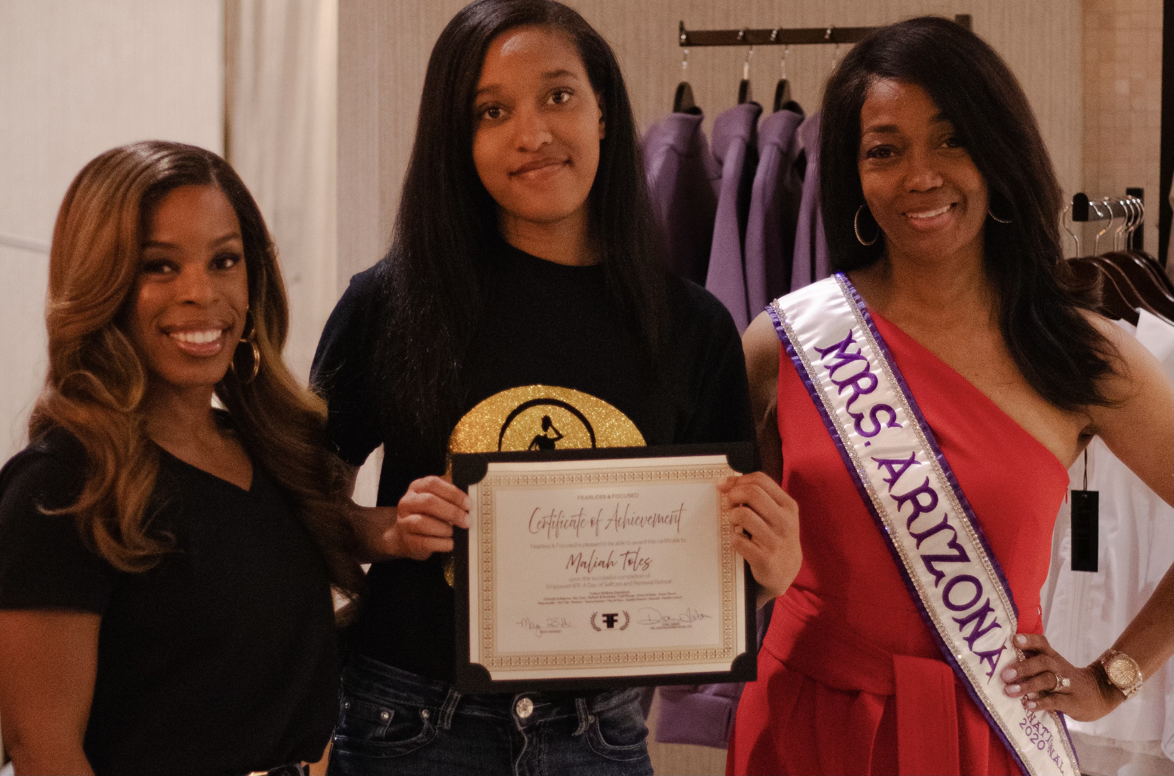 Doria Michelle Tabron, wearing her Mrs. Arizona sash, standing with a youth participant holding a certificate and another woman.
