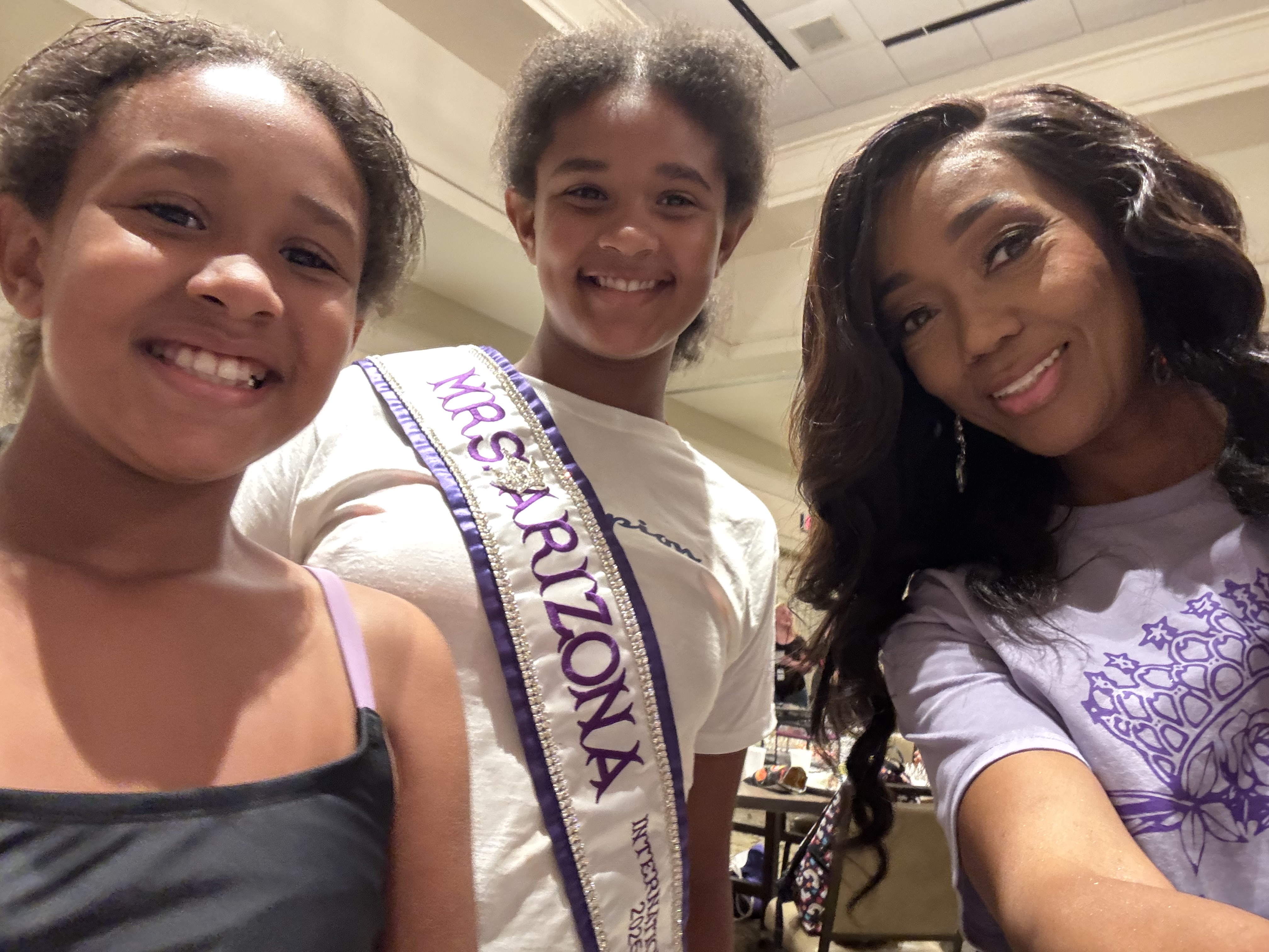 Doria Michelle Tabron wearing her sash and smiling alongside two young people at a community gathering.
