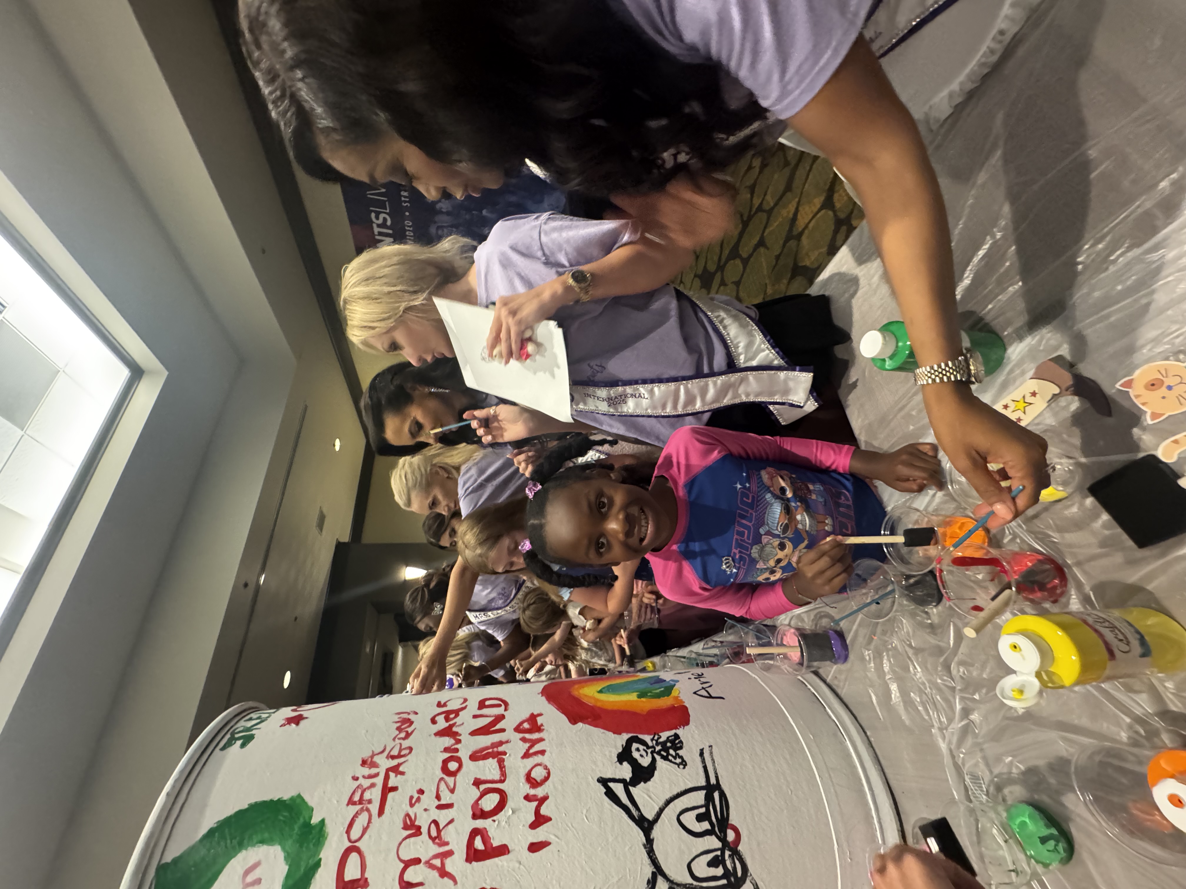 Doria Michelle Tabron engaging with a young participant during a community creative activity alongside other volunteers.