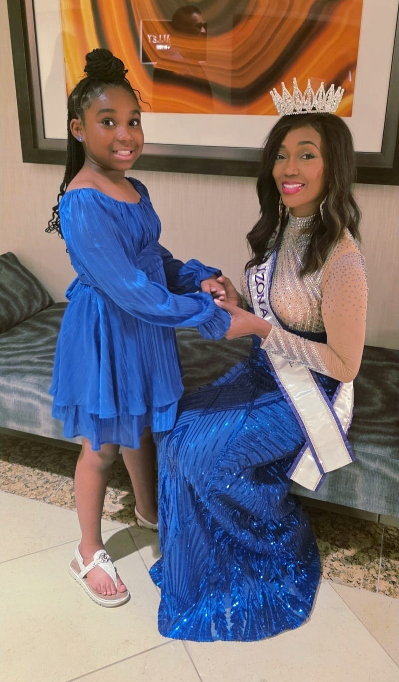 Laila Tabron standing with Doria Michelle Tabron, who is wearing her crown and international pageant sash.