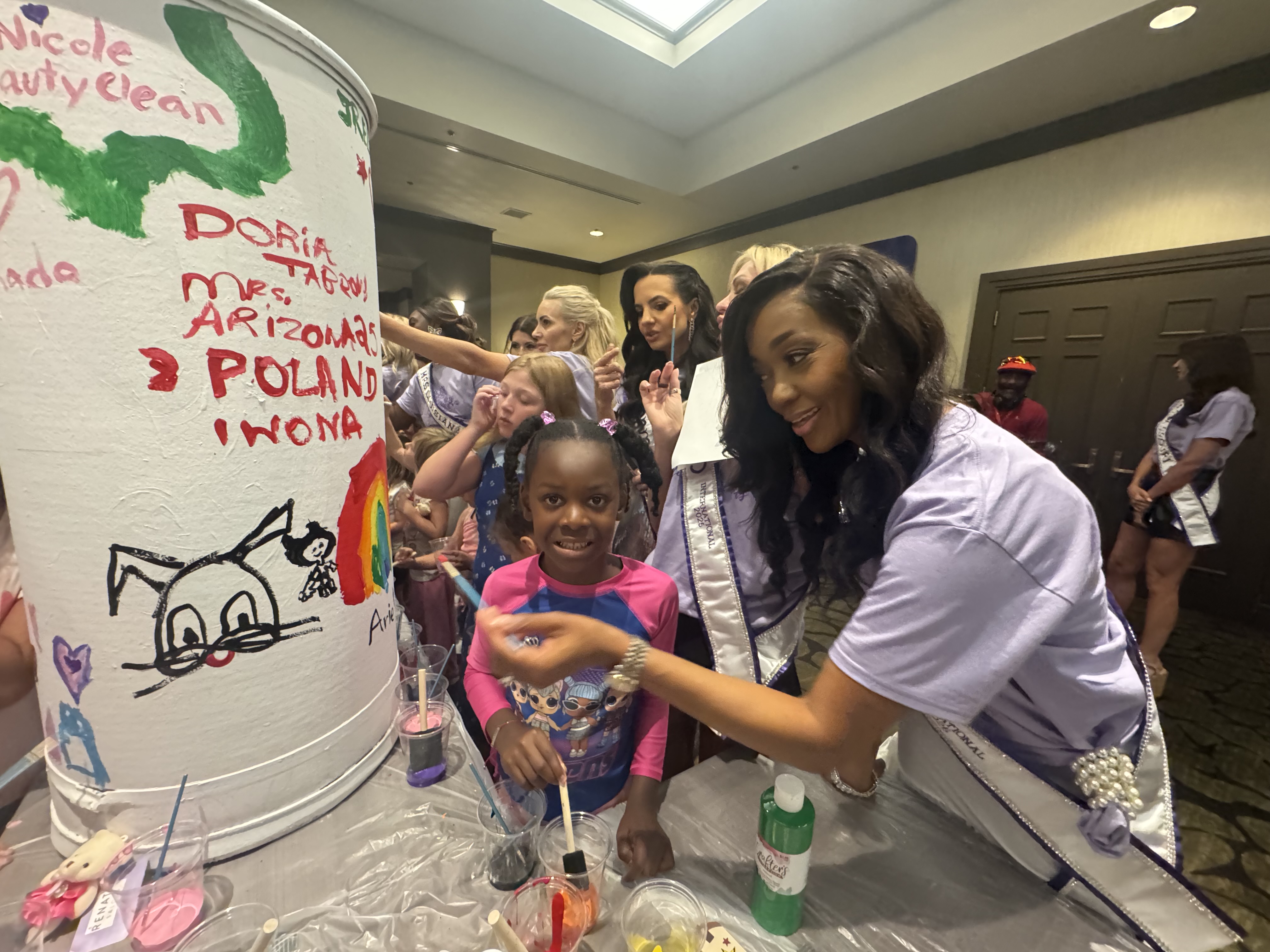 Doria Michelle Tabron helping a child paint during a community educational activity.